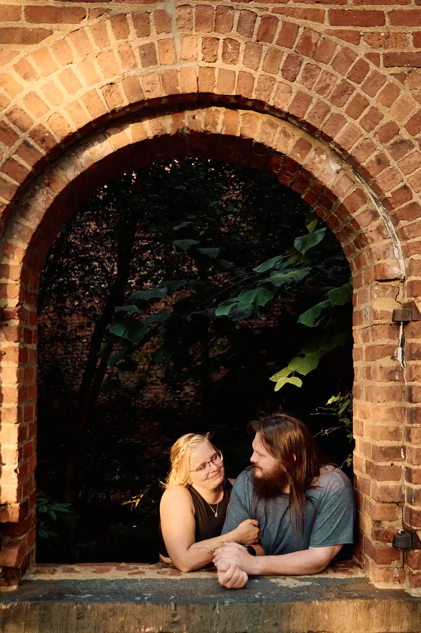 Couple running away through a long brick-paved stone arcade, holding hands