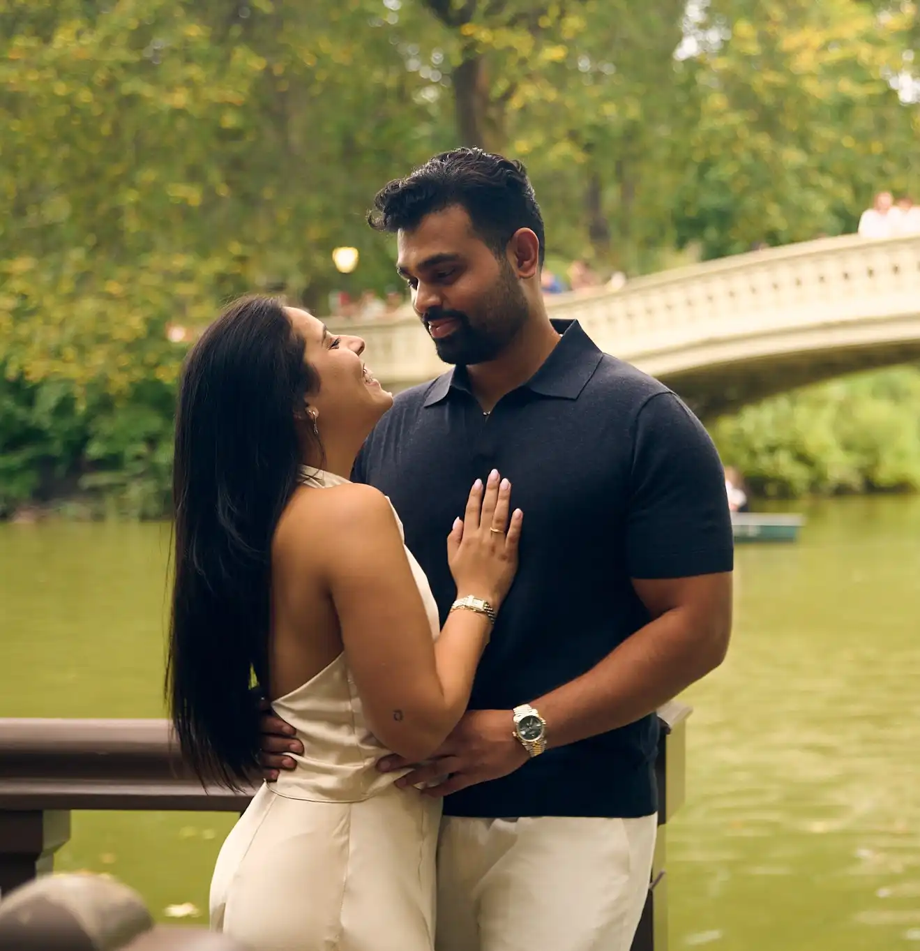 Couple holding hands at the edge of Central Park Lake, San Remo towers behind