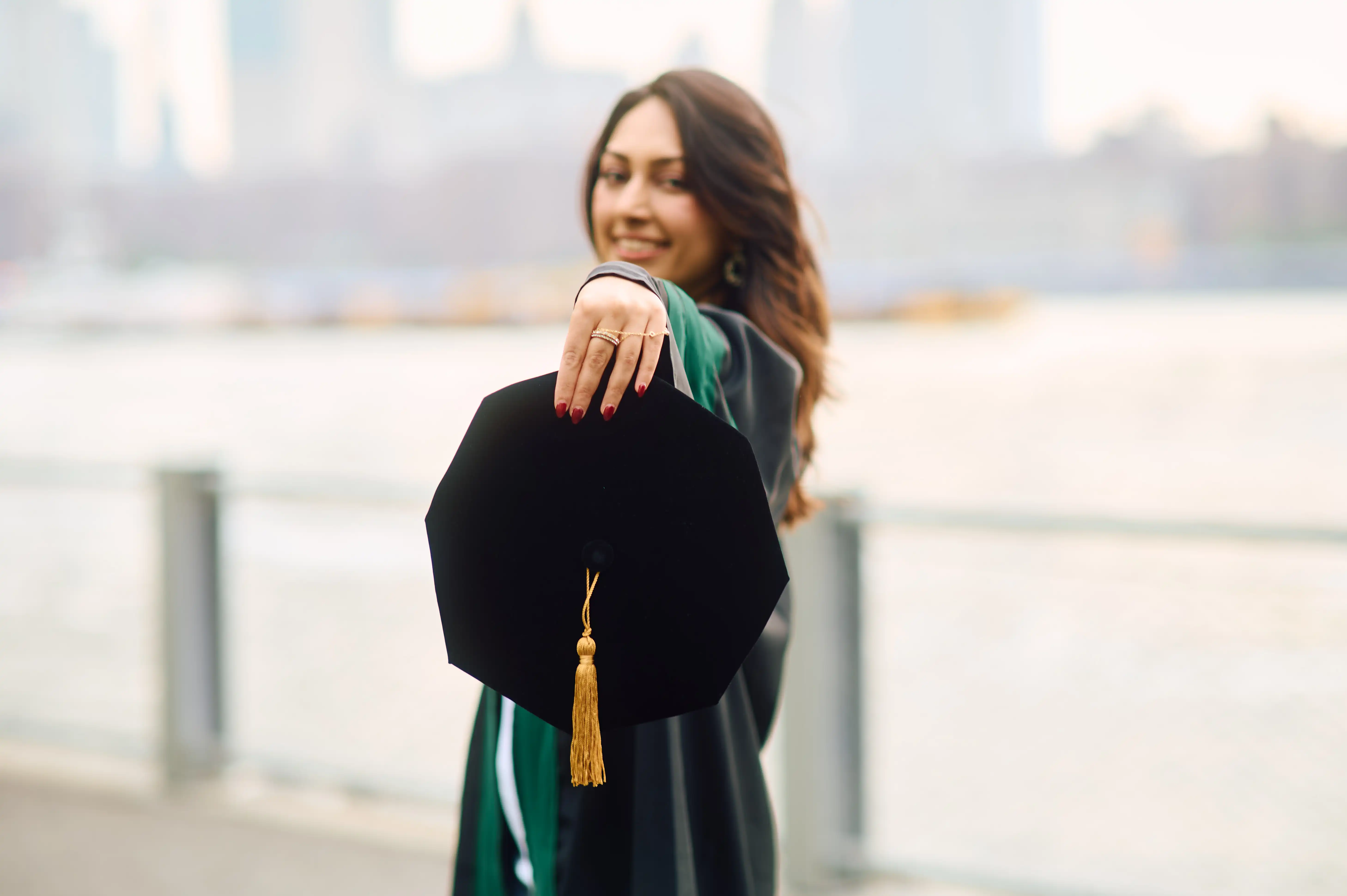 Three graduates throwing caps in front of Butler Library frieze with classical names